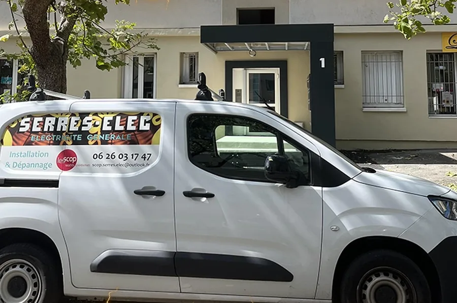 Véhicule utilitaire SERRES-ELEC floqué, stationné devant un pavillon.